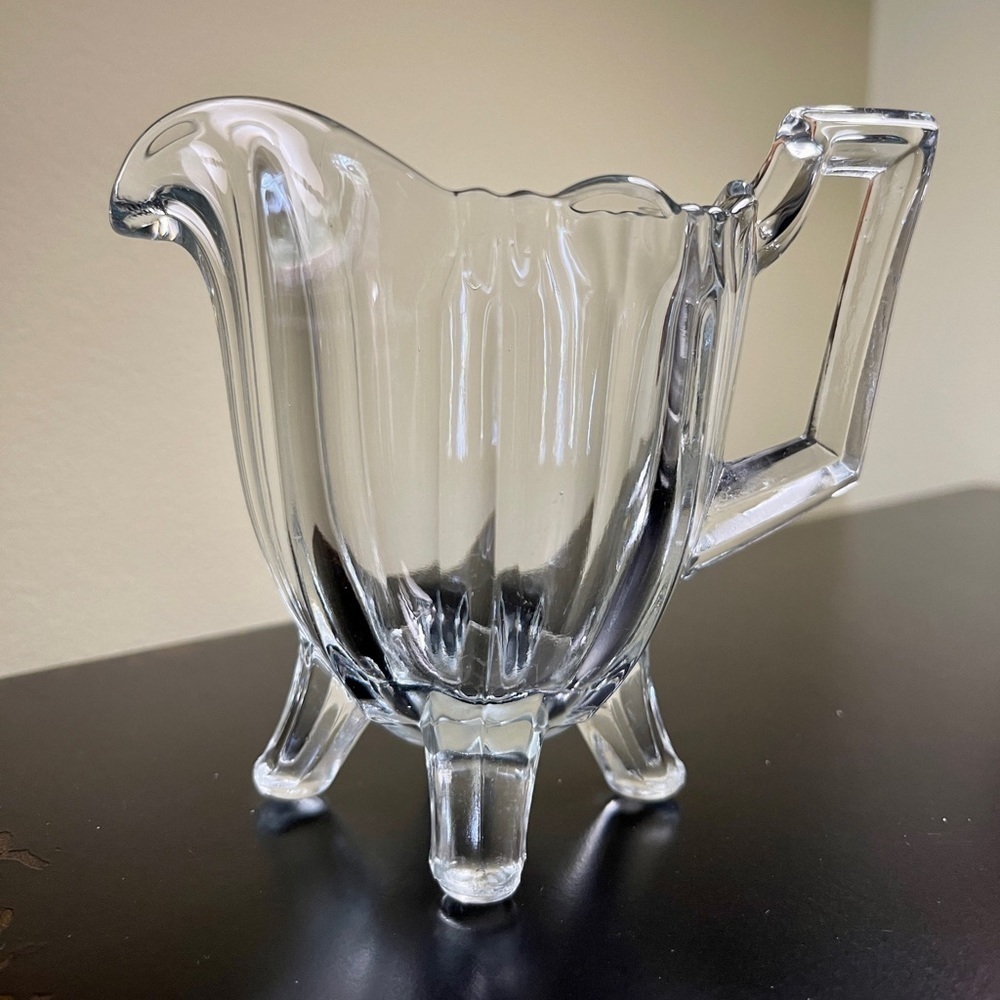 INDIANA GLASS, FOOTED, CLEAR GLASS CREAMER. 5”W(including handle)X 4 1/4”H X 3”D